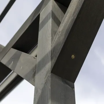 Zbliżenie węzła słupa z zastrzałami, w drewnie widoczne łby wkrętów ciesielskich
